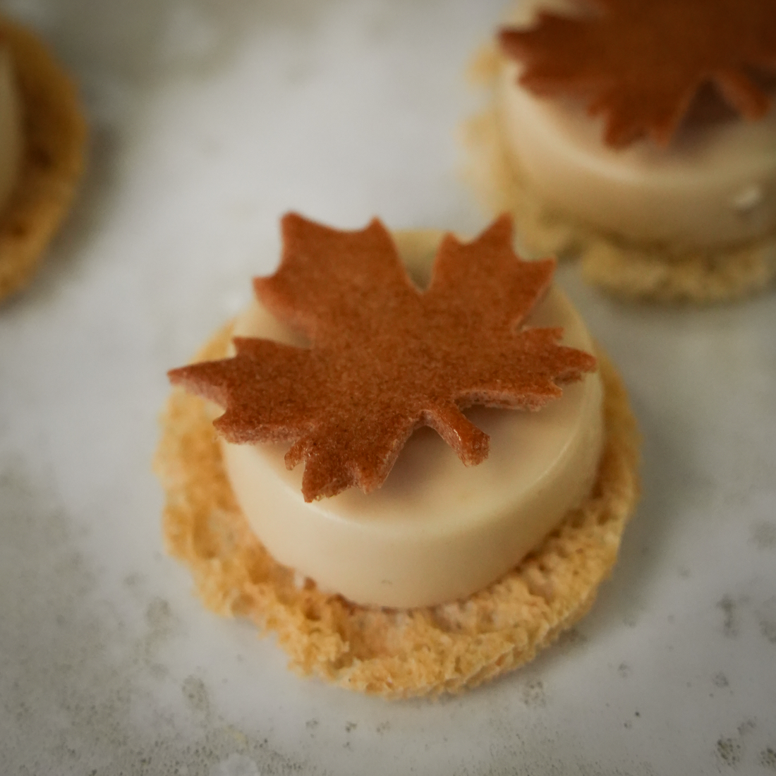 Gluten-free maple syrup tuile shaped like a leaf, crafted using the Maple Leaf silicone tuile mold by Toolculinair, featured in a recipe highlighting delicate sweet tuiles with rich flavor.