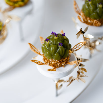 Top view of a finished artichoke-shaped piece plated on a pillar, surrounded by gold leaf decoration, created by Bocuse d’Or Netherlands for fine dining presentation.
