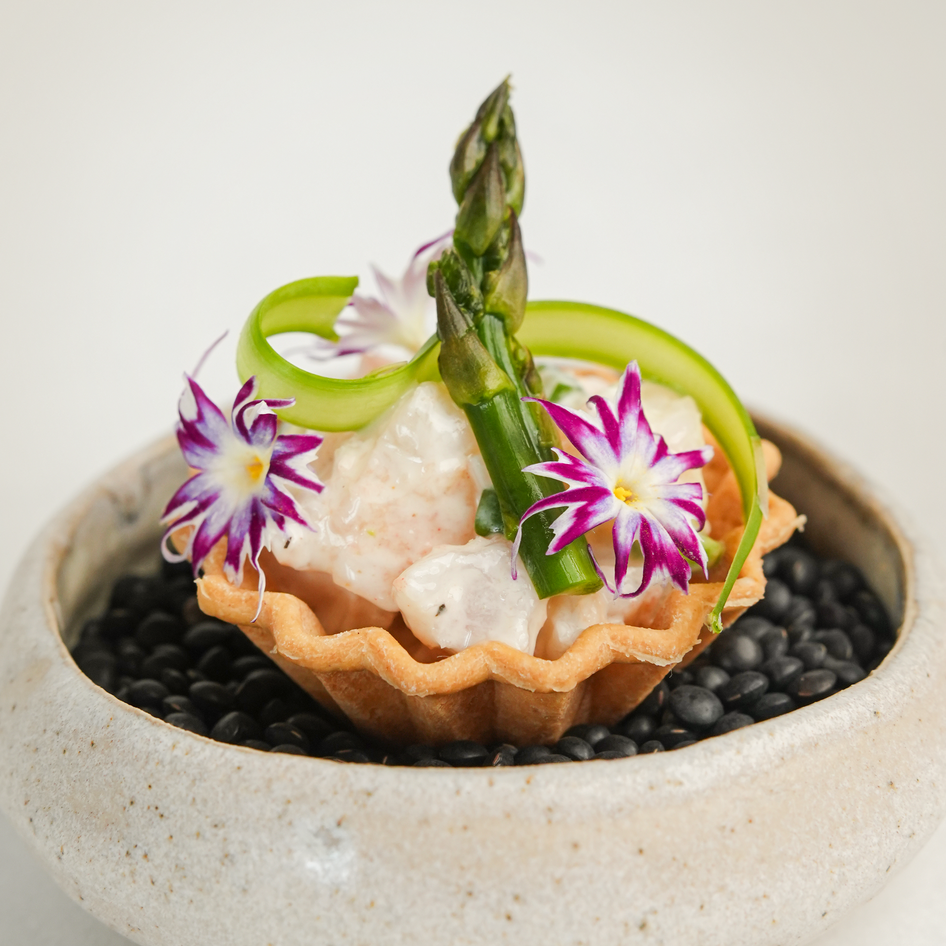 Photo of a crimped silicone tartelette mold dish filled with shrimp salad and green asparagus, showcasing a savory and elegant appetizer presentation.
