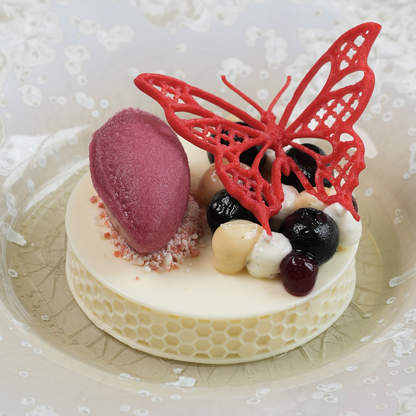Dessert plated at de Moerbei by Michael Corpel, topped with a red butterfly tuile, shown in a wider composition of the full dish presentation.
