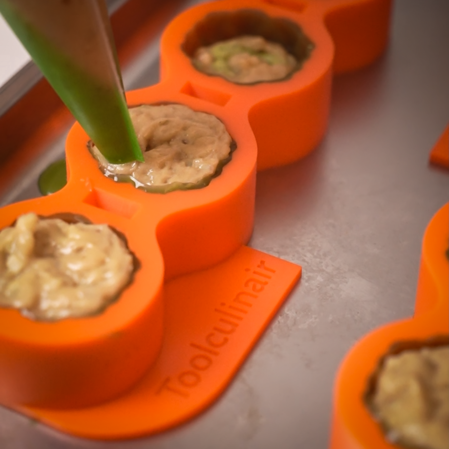 Orange Toolculinair silicone mold with visible logo being filled using a piping bag during mise en place practice for Bocuse d’Or competition preparation.